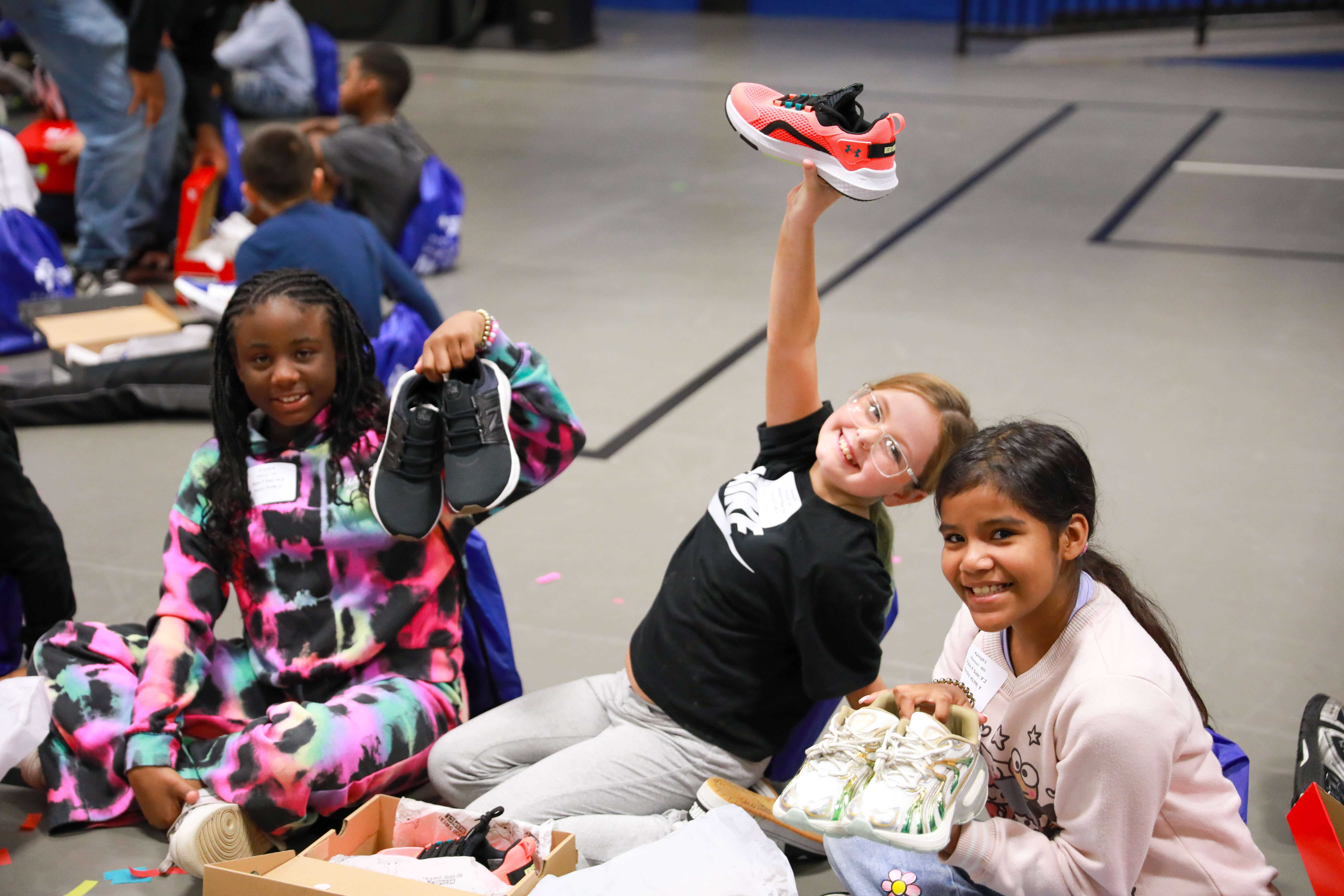 Weeden students hold up their new shoes. Kicks for Kids shoe drops are made possible because of generous donors in our community.